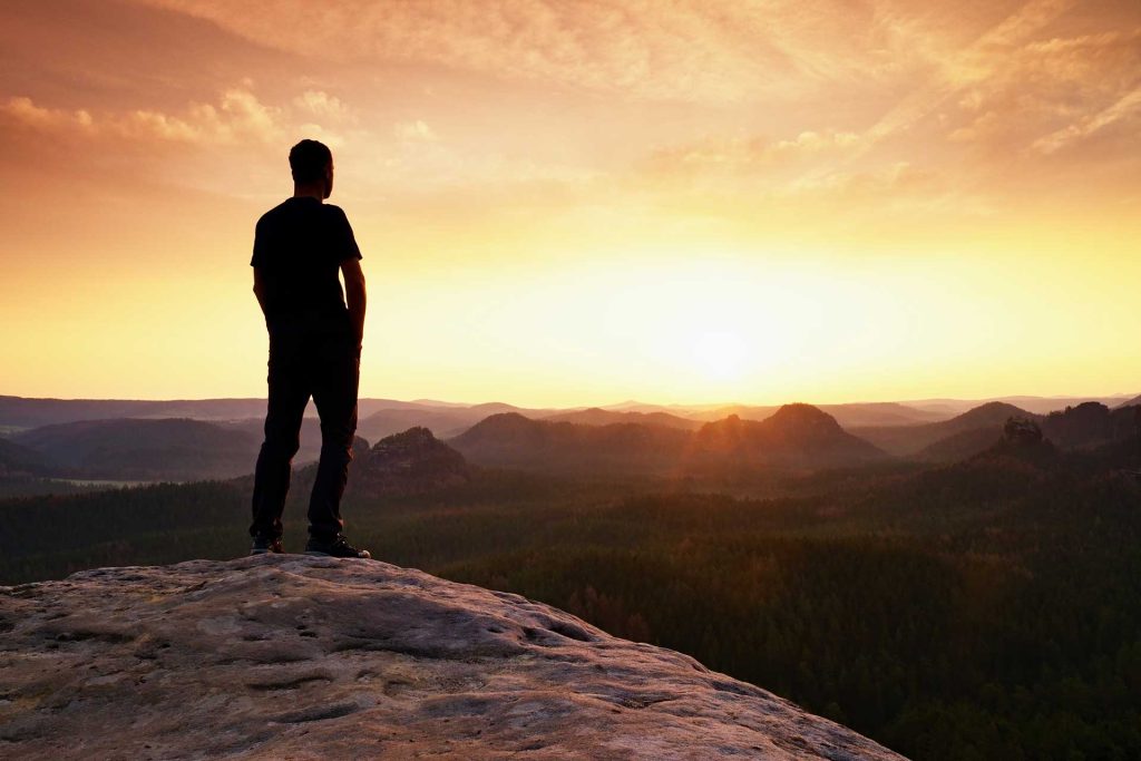 Person enjoying wellness at sunset on a cliff